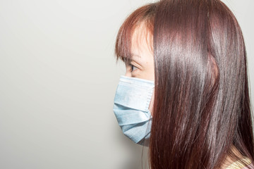 Side view of a Female asian wearing a mask to protect her against the corona virus.