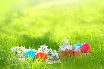 Christian Easter holiday concept. Easter cakes, orthodox sweet bread - kulich, flowers and colorful painted eggs in grass. copy space. 