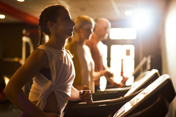Group of people exercising in a gym cardio training and running
