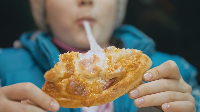 Child eat pizza cheese four. Close up of young girl woman mouth greedily eating pizza and chewing in outdoor restaurant. Kid children hands taking piece slice of hot tasty italian pizza from open box.