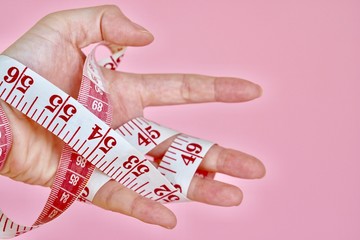 left hand wrapping with body tape measurement on the pink background