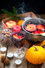 Obraz na płótnie Canvas Christmas red wine mulled wine with spices and fruits on a wooden rustic table. Traditional hot drink for Christmas. Mulled wine hot drink with citrus fruits, apples and spices in a pan. Hot drink