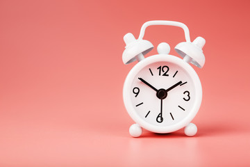 White retro alarm clock on pink background. Concept of time with free space for text.