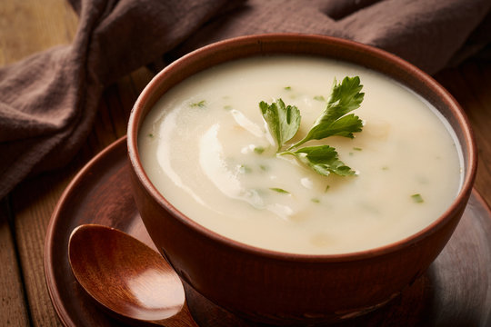 Bowl of potato soup with parsley on a wooden background