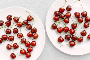 Cherries on two plates on concrete background.
