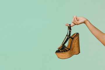 Female hand holds summer sandals on a blue background, copyspace