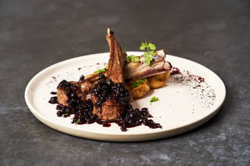 Lamb ribs with baked potatoes on a white plate, close-up.