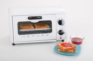 Household kitchen utensils; Small white toaster oven.