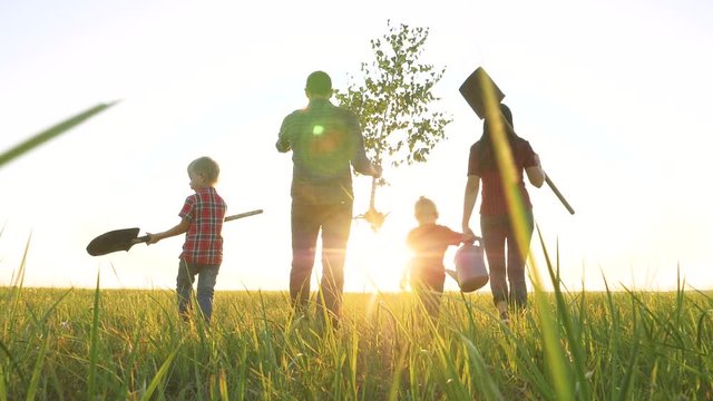 agriculture red neck farming happy family walking agriculture of farmers a silhouette concept slow motion video. mom dad son and daughter walk go children happy family plant and water the tree