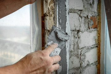 The plasterer repairs the corners of the window with a spatula and plaster. Construction finishing...