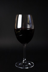 A glass with red wine on the black backround