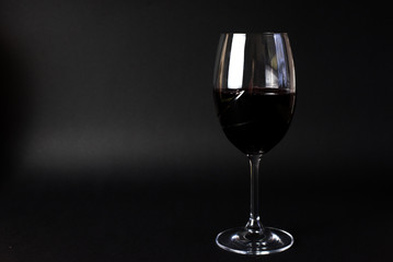A glass with red wine on the black backround