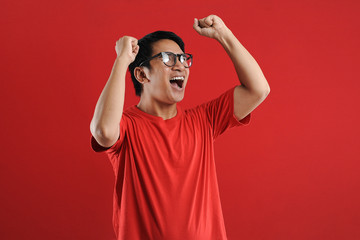 Young asian man happy and excited expressing winning gesture. Successful and celebrating