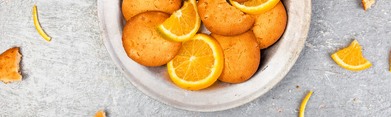 Banner of Cookies and orange citrus fruit on metal plate on grey background.
