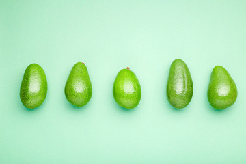 Fresh ripe organic green avocados on color background, top view summer food concept. Minimal flat lay style avocado whole fruit on mint green background.