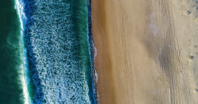 Aerial view of a wave breaking at the shore of the Comporta Beach in Portugal.