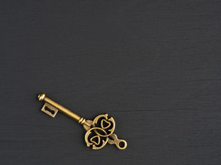Old bronze antique key on black wooden background with copy space