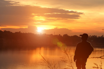 Fototapeta premium The silhouette of a person sitting and watching the sunset