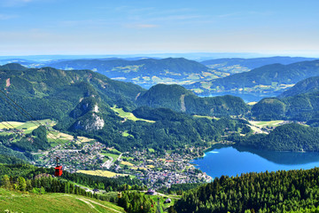 Fototapeta na wymiar Zwolferhorn, green mountains and fields in Austria, trees and lakes, a bird's-eye view of the city, in the spring afternoon.