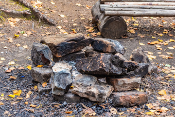 Gray and brown big stones for a bonfire are in a round fire in a autumn forest