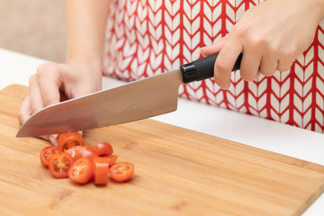 Cooking Salad. Female hands cut cherry tomatoes for Caesar.