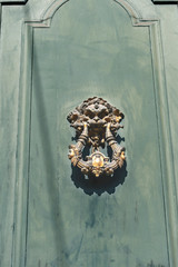 Old metal door handle in the shape of a lion's head with a ring in his mouth on a wooden background