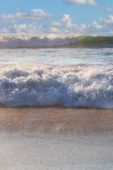 large ocean waves bump into the hot summer sand of a beach near the Portuguese city of Sintra