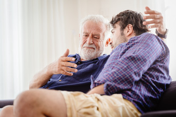 old man serious discussion with younger man indoor, grand father serious talking with his son at...