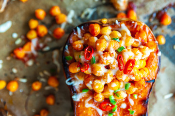 Close up shot of a roasted butternut squash topped with chickpea, pepper and cheese