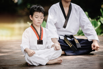 Fighter kid in Taekwondo uniform sitting concentration for training self defense body and mild.