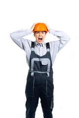 young woman in a uniform and a helmet, a worker, a master is surprised and scared. the girl clutched her head in horror. isolated