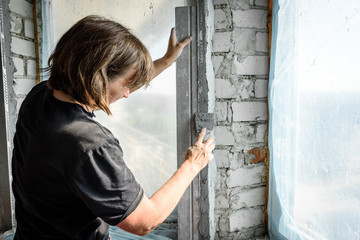 The plasterer repairs the corners of the window with a spatula and plaster. Construction finishing works.