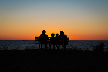 Naklejka na ściany i meble family watching the sunset on the beach