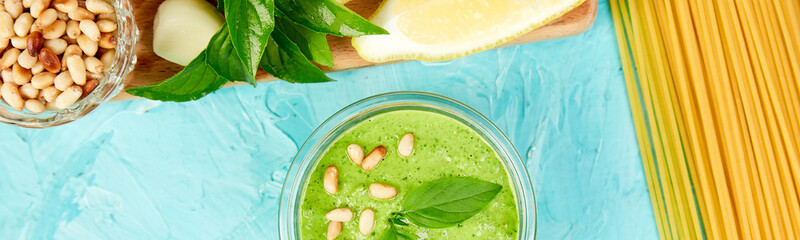 Banner of Homemade pesto sauce in glass jar with ingredients.