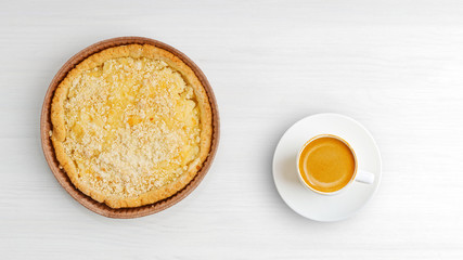 Closeup homemade cheesecake with streusel and cup of coffee on white wooden table. Top view. Copy space.