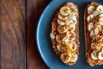 Close up shot of a slices of bread topped with peanut butter, honey and banana slices
