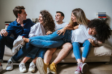 Portrait of a group of friends sitting on the sofa at home - Millennials have fun together in an...