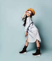 Little asian kid in sunglasses, oversized shirt dress, brown beret, boots. She kissing you, posing...