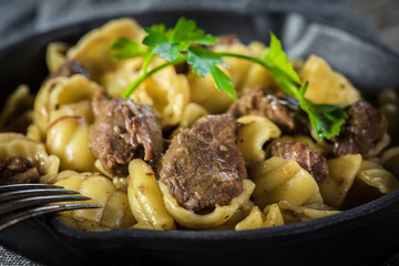 Italian pasta shells with beef sauce in cast iron pan.