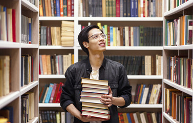 Young chinese man in glasses standing at library