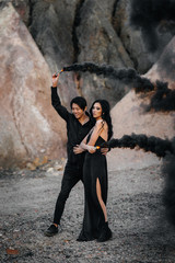 An Asian couple in love lit black smoke bombs in the mountains. Colored smoke