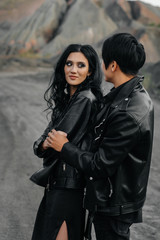 An Asian couple in love in black leather clothes walk in nature among the trees. Style, fashion, love