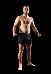 Brutal muscular sportsman standing in black shorts.