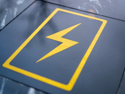 Wireless built-in charging station for smartphone and tablet. The charge sign is shown on a black table in a cafe, close-up. Free charging station for electronic devices in a public place
