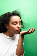 Beautiful African girl smelling her perfume on green background 