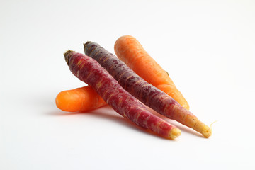 Black carrots and orange carrots over white background