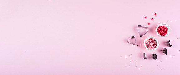 Banner for website design. Valentine's day background. Cooking background with cookie cutters and pink sugar sprinkling on pink background. Flat lay, top view, copy space