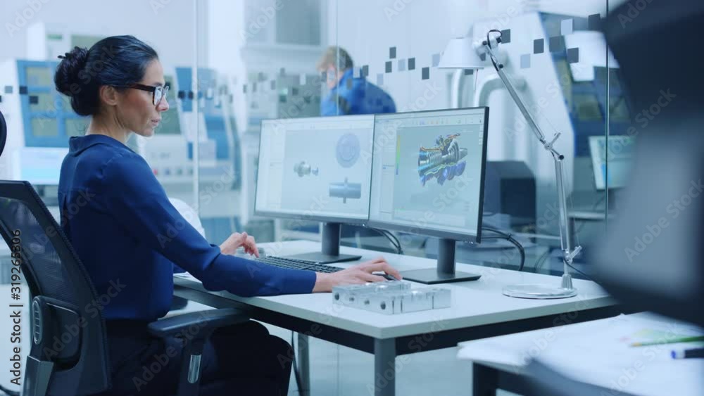 Poster Female Industrial Engineer Solving Problems, Working on a Personal Computer, Two Monitor Screens Show CAD Software with 3D Prototype of Engine Being Tested. Working Modern Factory