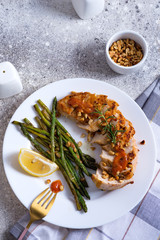 Grilled chicken breast with grilled asparagus and lemon slice on stone. Paleo diet. Concept for a tasty and healthy meal.