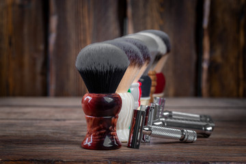 Metallic safety razors and shaving brushes on rustic wooden boards background, barber shop concept